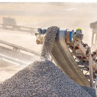 Mineral processing plant conveyor discharging crushed ore illustrating beneficiation and throughput optimization.